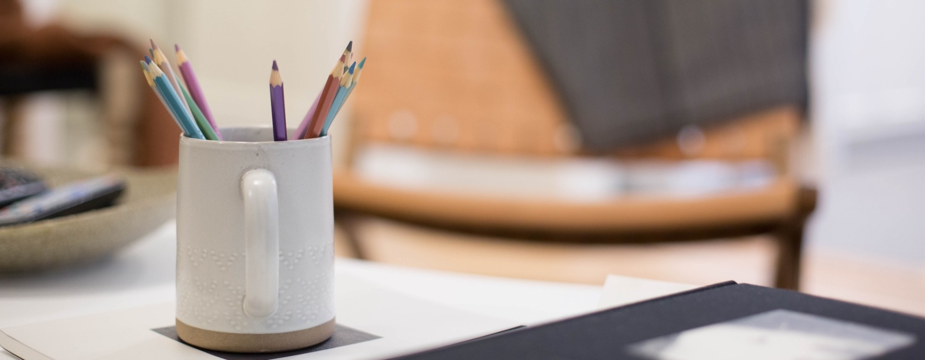 a desk with a coffee cup full of colored pencils