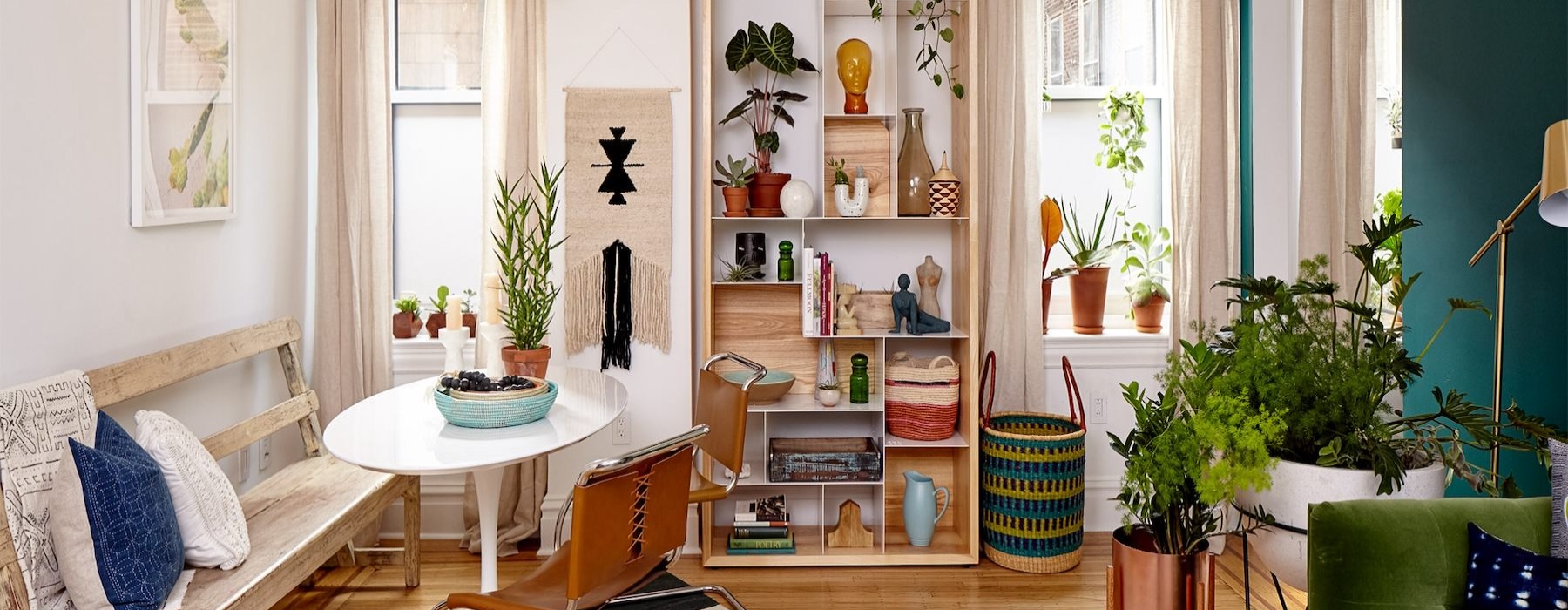 living room with bookshelf plants seating and tables