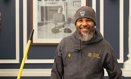 a man smiling with a mop handle in view